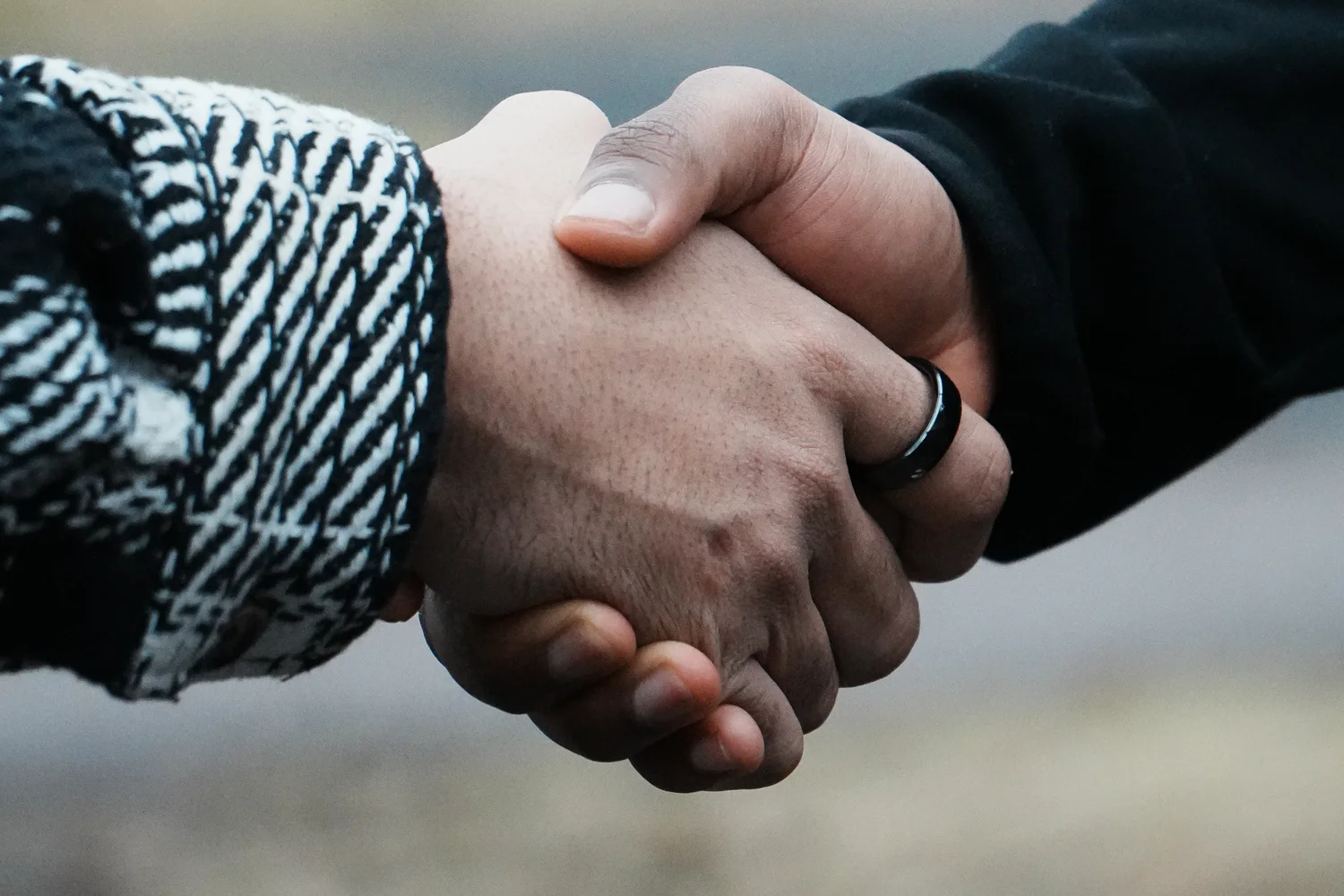 A handshake with a Ping ring visible